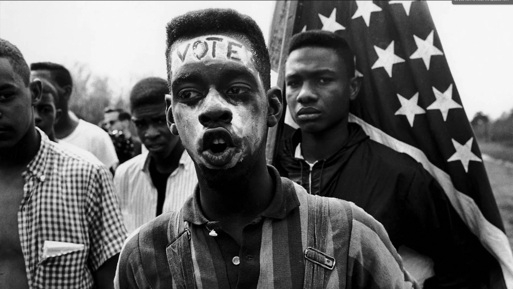 Young man with "Vote" painted on his forehead walking in the Selma March. Selma, Alabama. USA. 1965. © Bruce Davidson