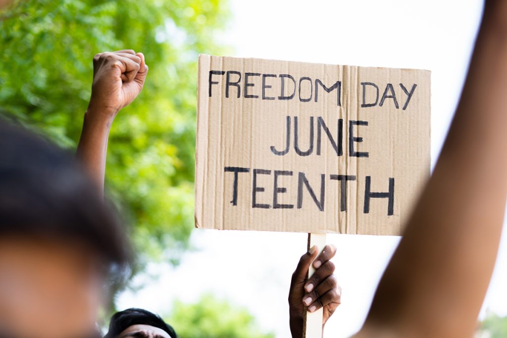 people holding up Juneteenth sign