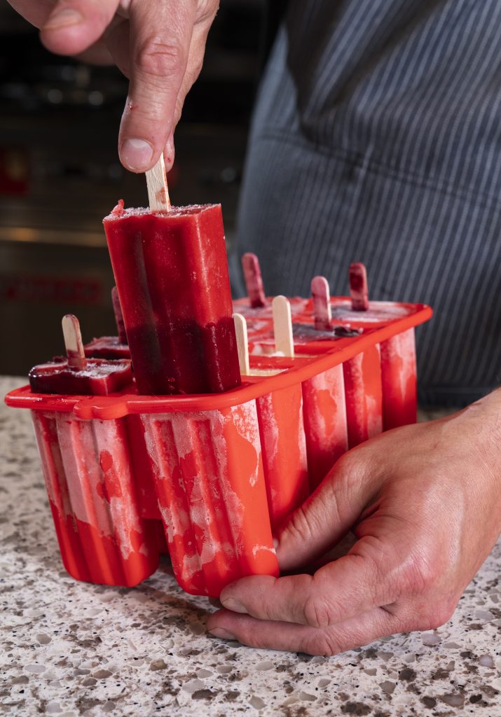 Chef Brook Harlan pulls out frozen popsicle from red mold