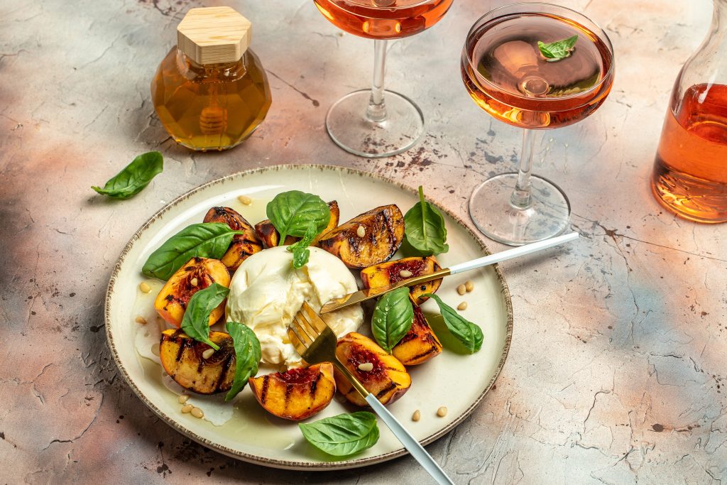 burrata,cheese,and,grilled,peaches,with,rose,wine.,top,view.