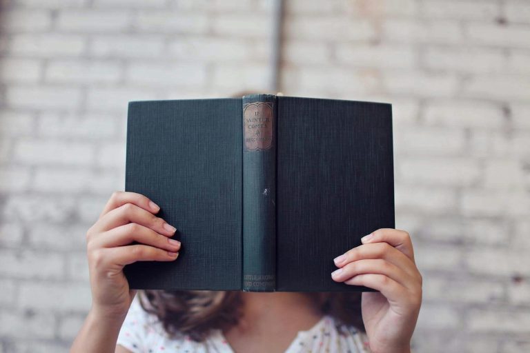 woman holding up book in front of her face