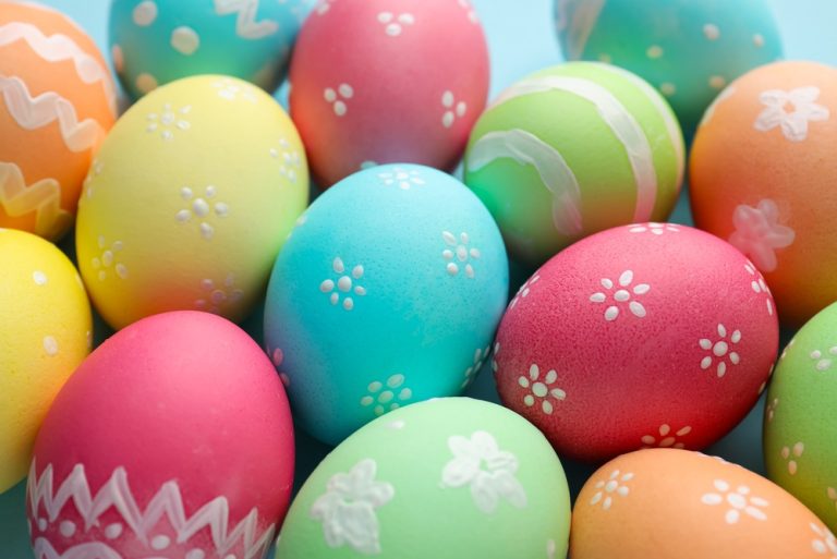 many,painted,easter,eggs,on,light,blue,background,,closeup