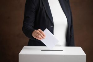 woman,hand,throws,voting,ballot,paper,in,ballot,box,,concept
